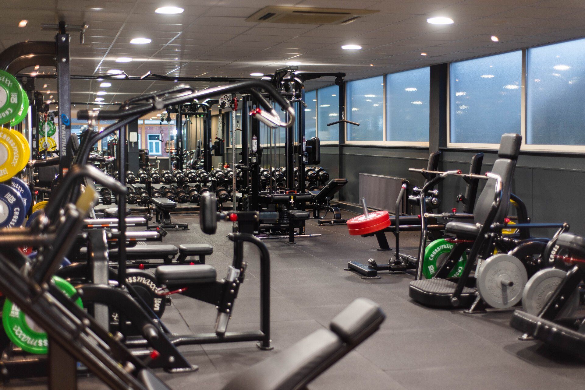 Interieur van de sportschool met diverse gewichtsmachines en apparatuur.