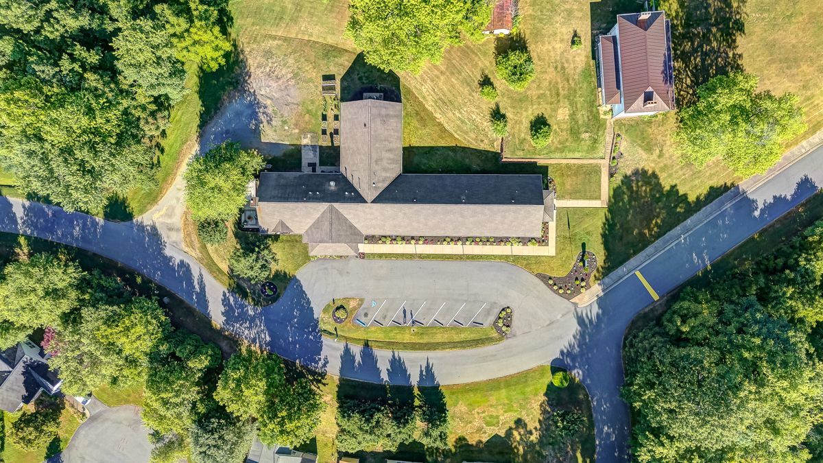 An aerial view of a house surrounded by trees and a road.