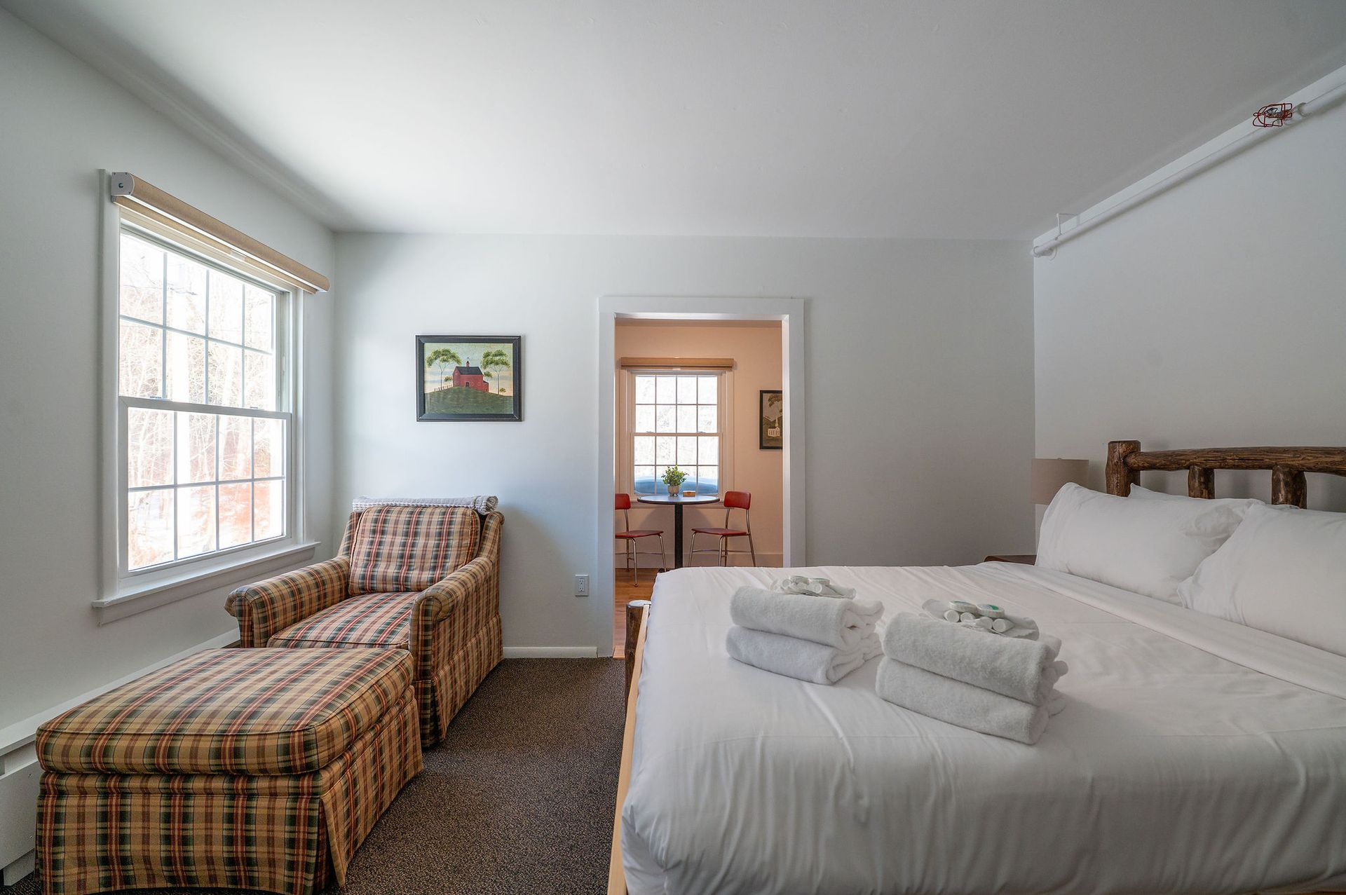 Bedroom with king bed, patterned armchair, window, and doorway to a dining area.