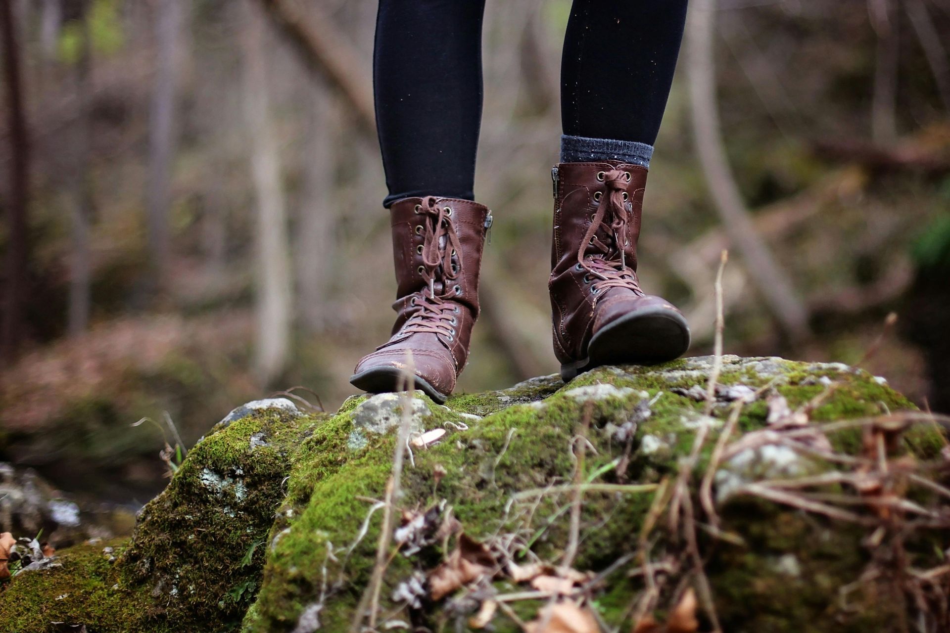 Woman hiking rocky trail in mountains, arms outstretched, backpack, scenic view.