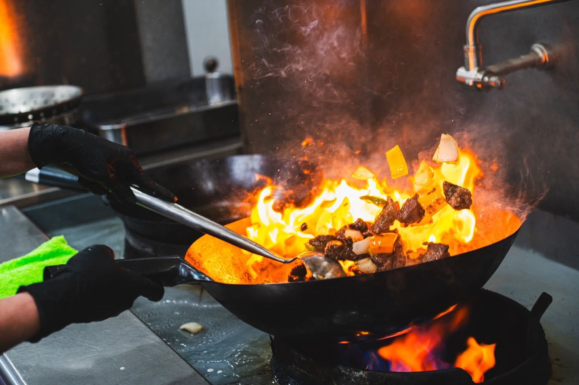 Image of meat and vegetables cooking in a wok with a fire