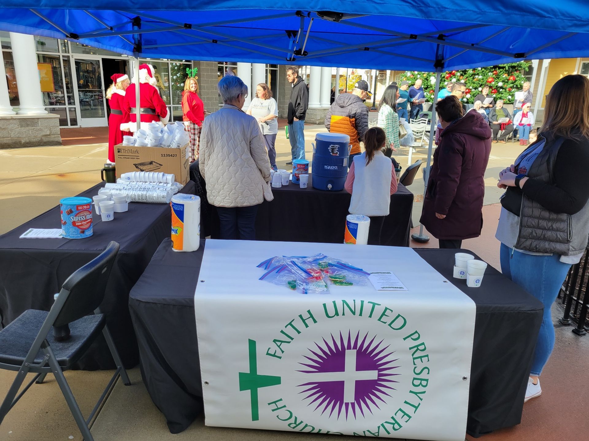 Faith United Presbyterian outreach table under blue canopy with church banner and volunteers at a community event