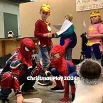 Children in Spider-Man costumes perform in a Christmas play on a stage.