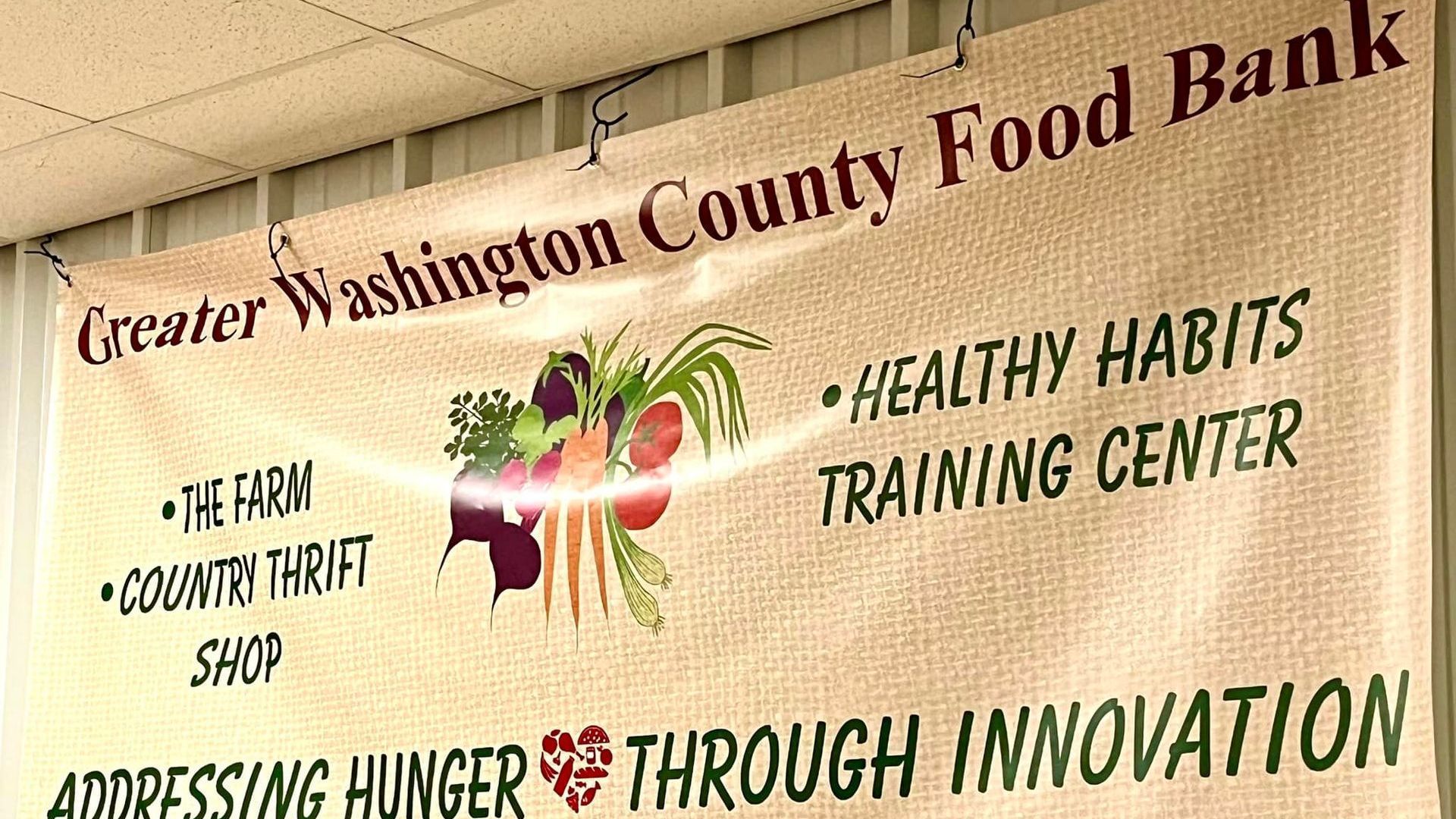 Banner for Greater Washington County Food Bank with farm, community shop, and health habits training center text