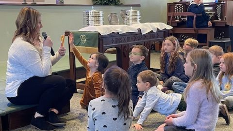 Teacher showing a toy to a small group of children seated on the floor in a classroom