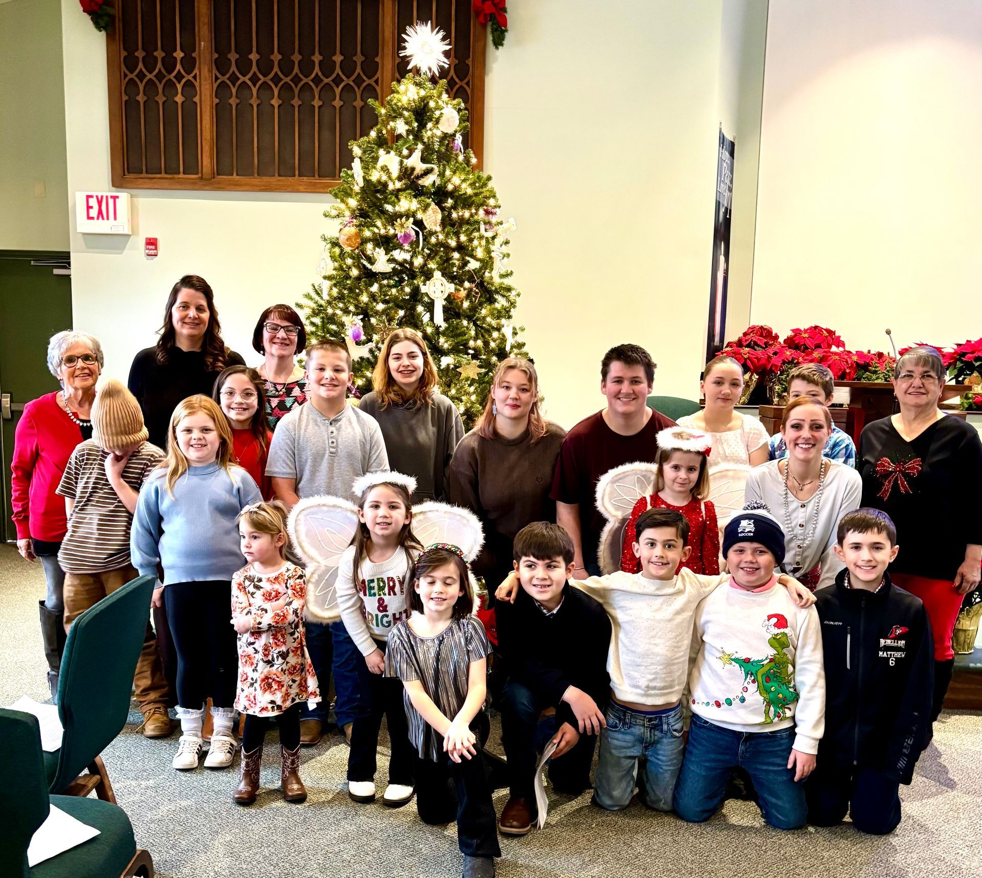 Group of people posing indoors in front of a decorated Christmas tree and holiday decorations.