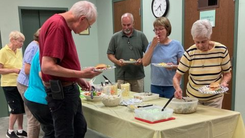 People serving themselves from a buffet table in a community room