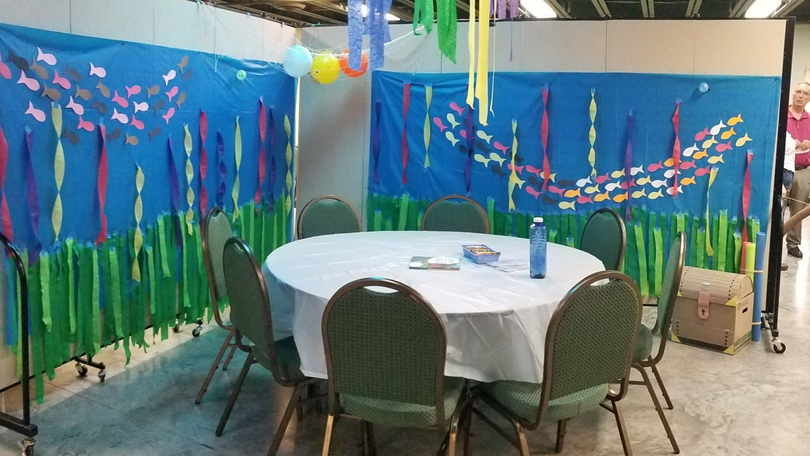 Round table with chairs in a blue-decorated party room with colorful streamers and balloons