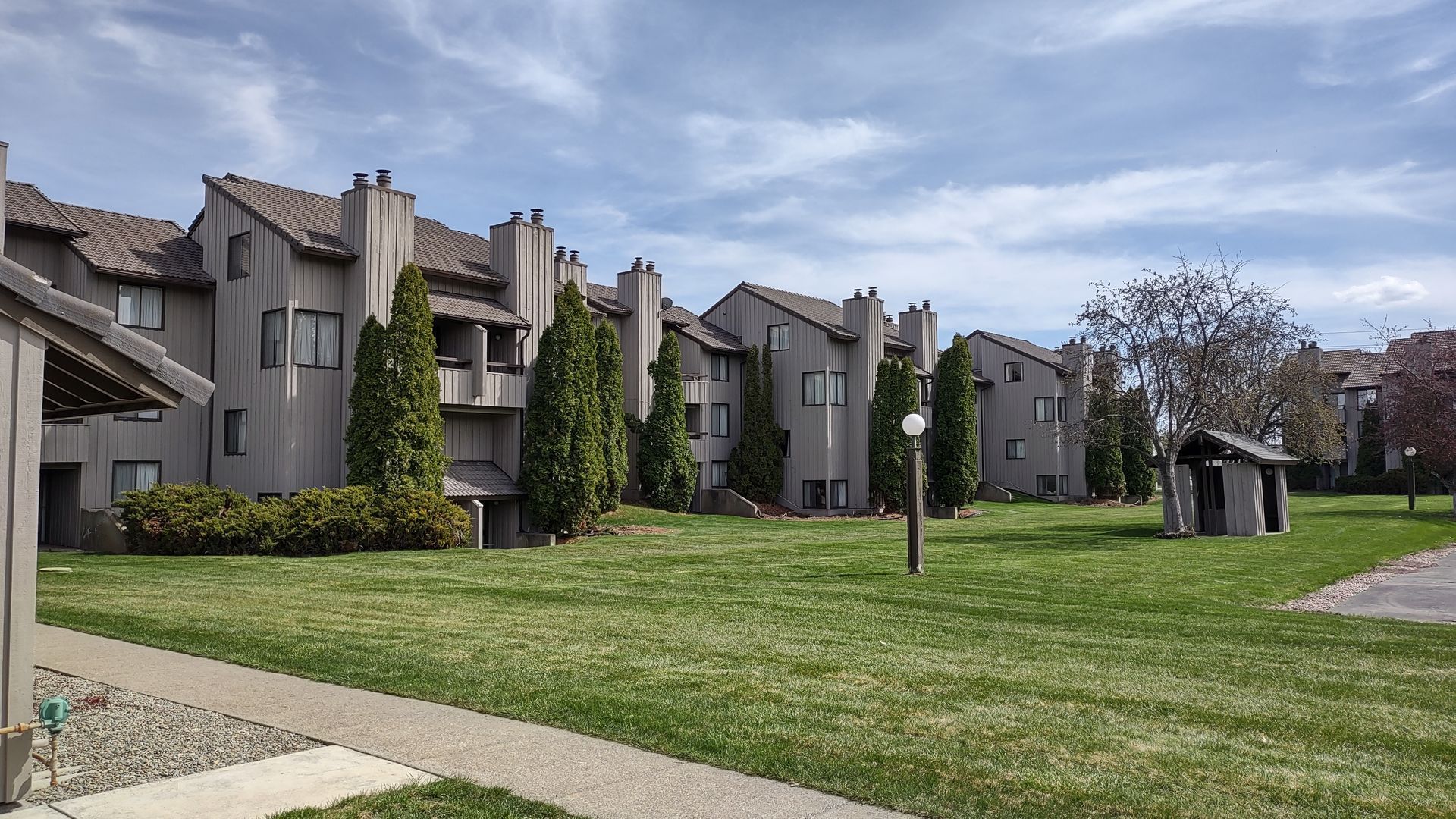 A row of apartment buildings with a lush green lawn in front of them.