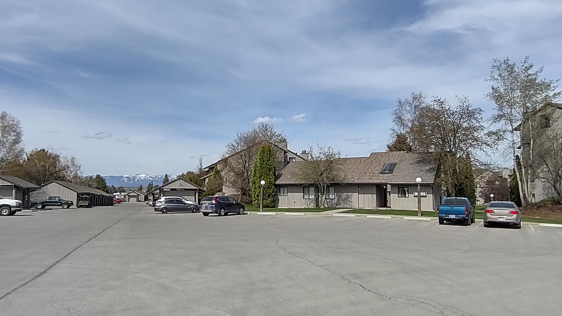 A parking lot with cars parked in front of a row of houses.