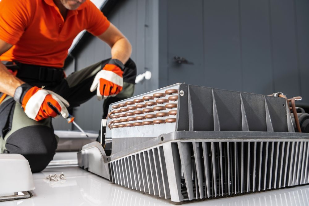Technician in orange gloves repairing rooftop HVAC unit with exposed components