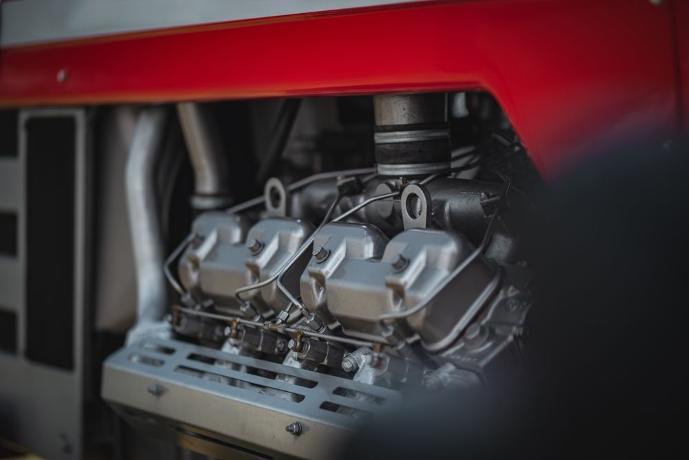 Close-up of a red race car engine with metallic components exposed behind the bodywork
