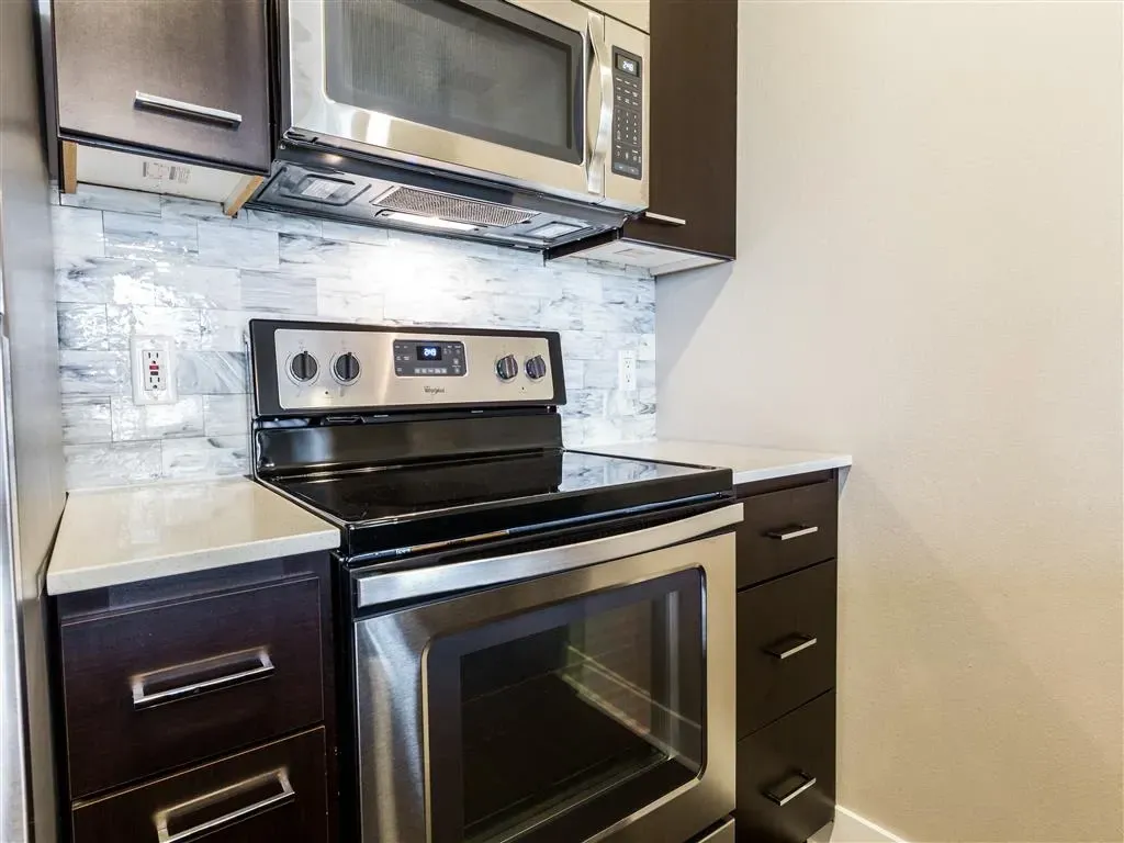 Stainless steel stove and microwave in a dark wood cabinet kitchen.