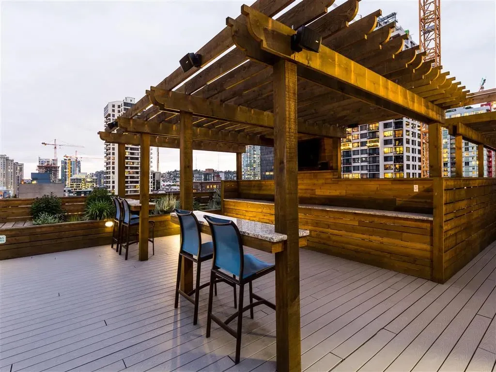 Rooftop deck with a wooden pergola, seating, and city views.
