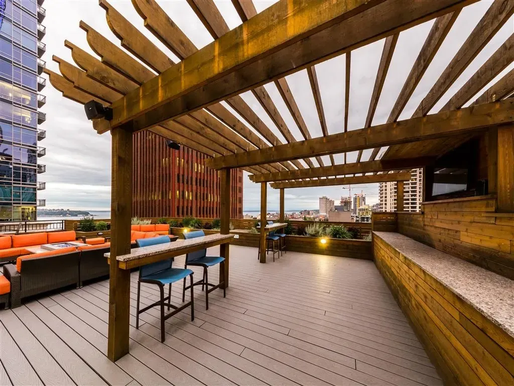 Rooftop terrace with a wooden pergola, outdoor seating, and city views.