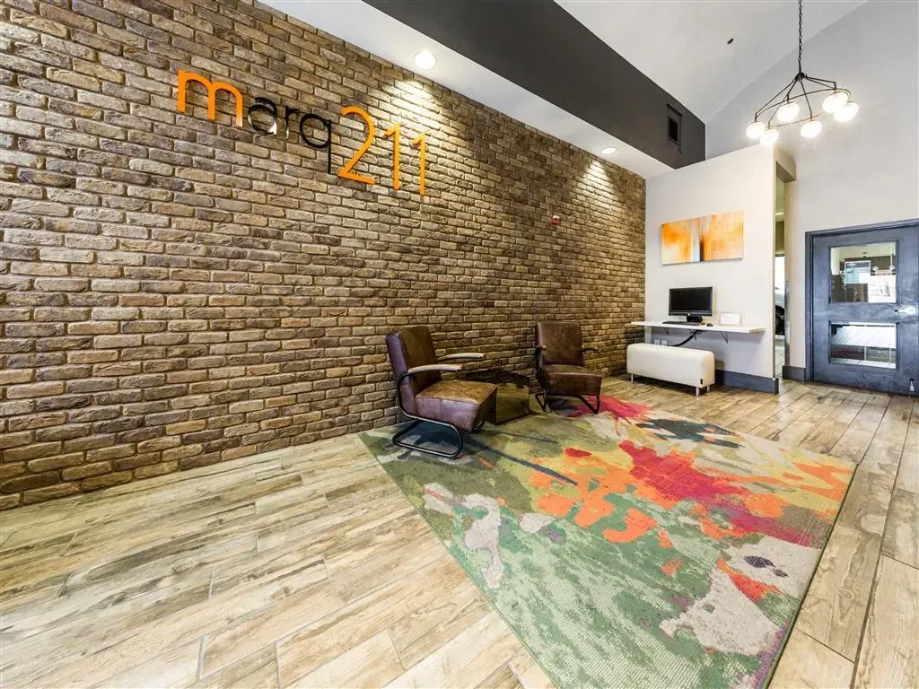 Entrance lobby of Marq211 apartments with brick accent wall and modern seating area.