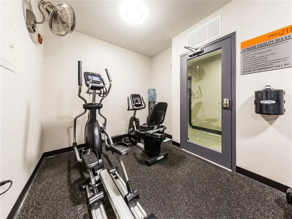 Fitness center with cardio equipment like ellipticals and recumbent bikes, plus a water cooler.