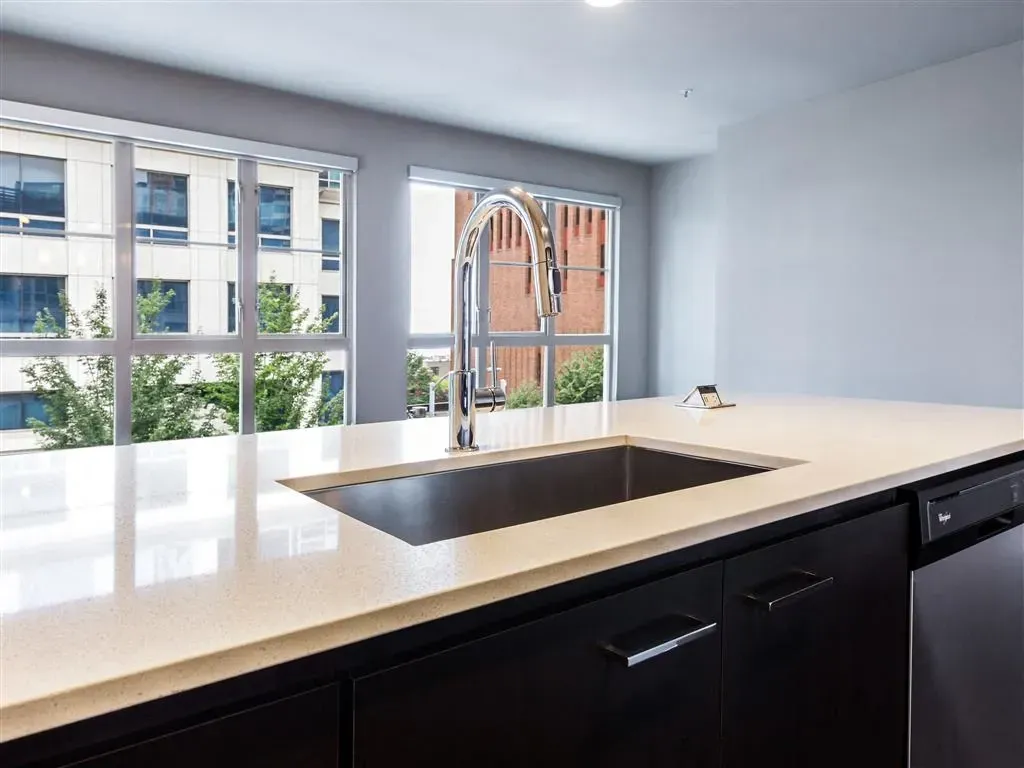 Kitchen island with sink and faucet, overlooking city buildings.