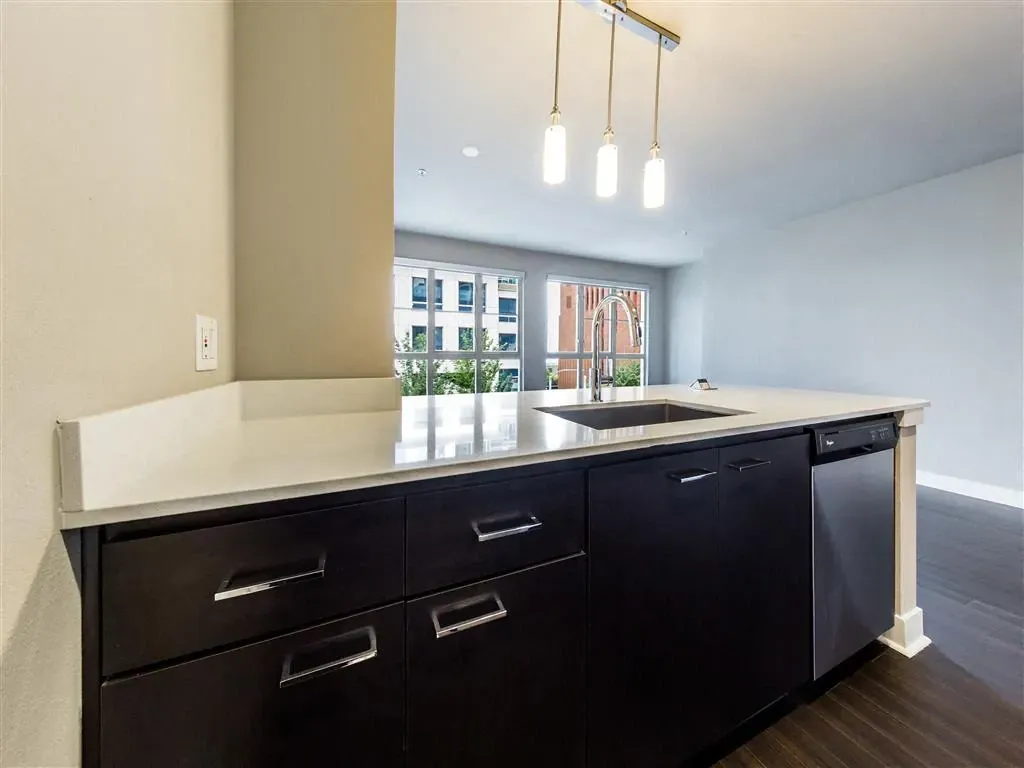 Modern kitchen island with a sink, dishwasher, and pendant lights.