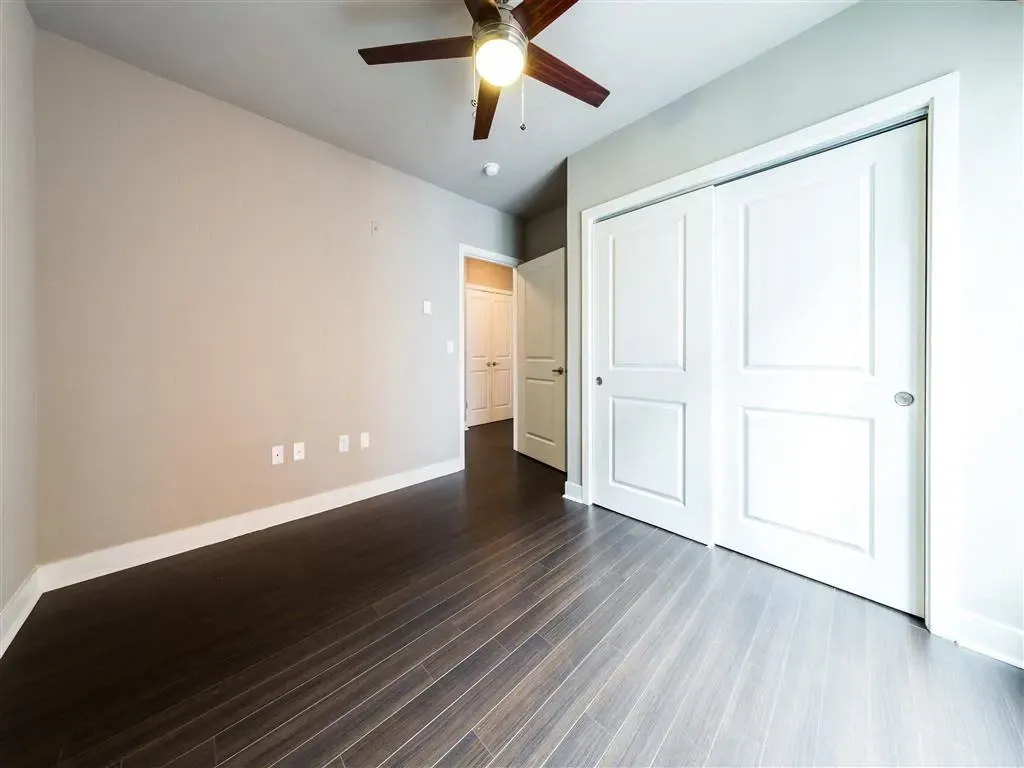 Empty bedroom with a ceiling fan and closet.