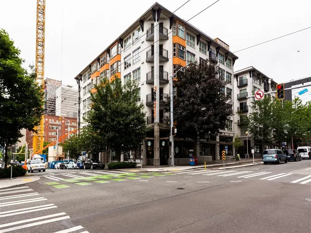View of apartment buildings and surrounding city street with a crane in the background.