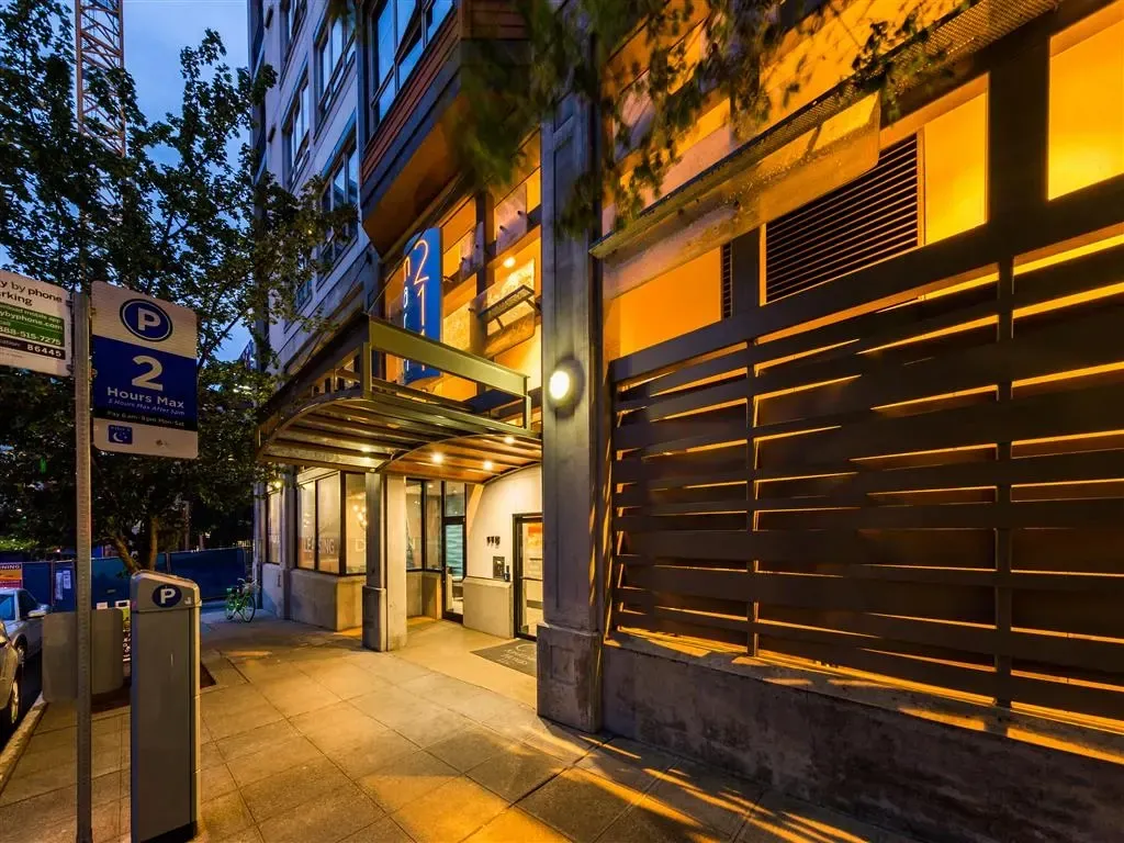 Modern apartment building entrance with illuminated canopy and modern horizontal siding.