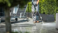 Person vacuuming a gray floor with a yellow vacuum in a modern living room
