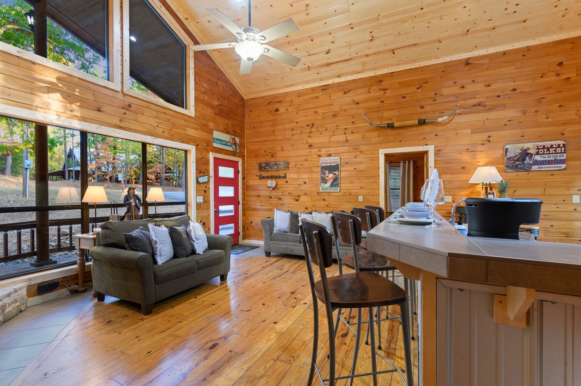 A living room in a log cabin with a couch , fireplace and television.