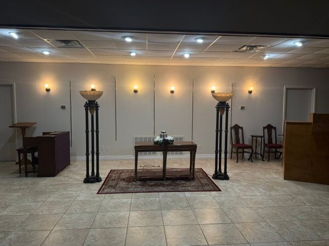 Dimly lit chapel with altar table, candlesticks, tiled floor, and chairs along the back wall.