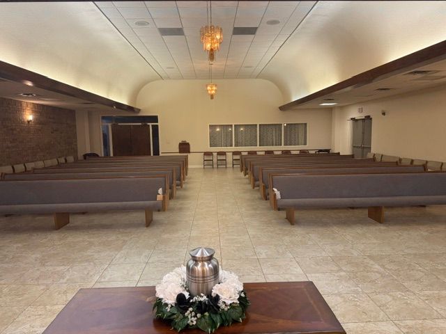 Empty church sanctuary with rows of pews, central aisle, and a floral arrangement on the front table