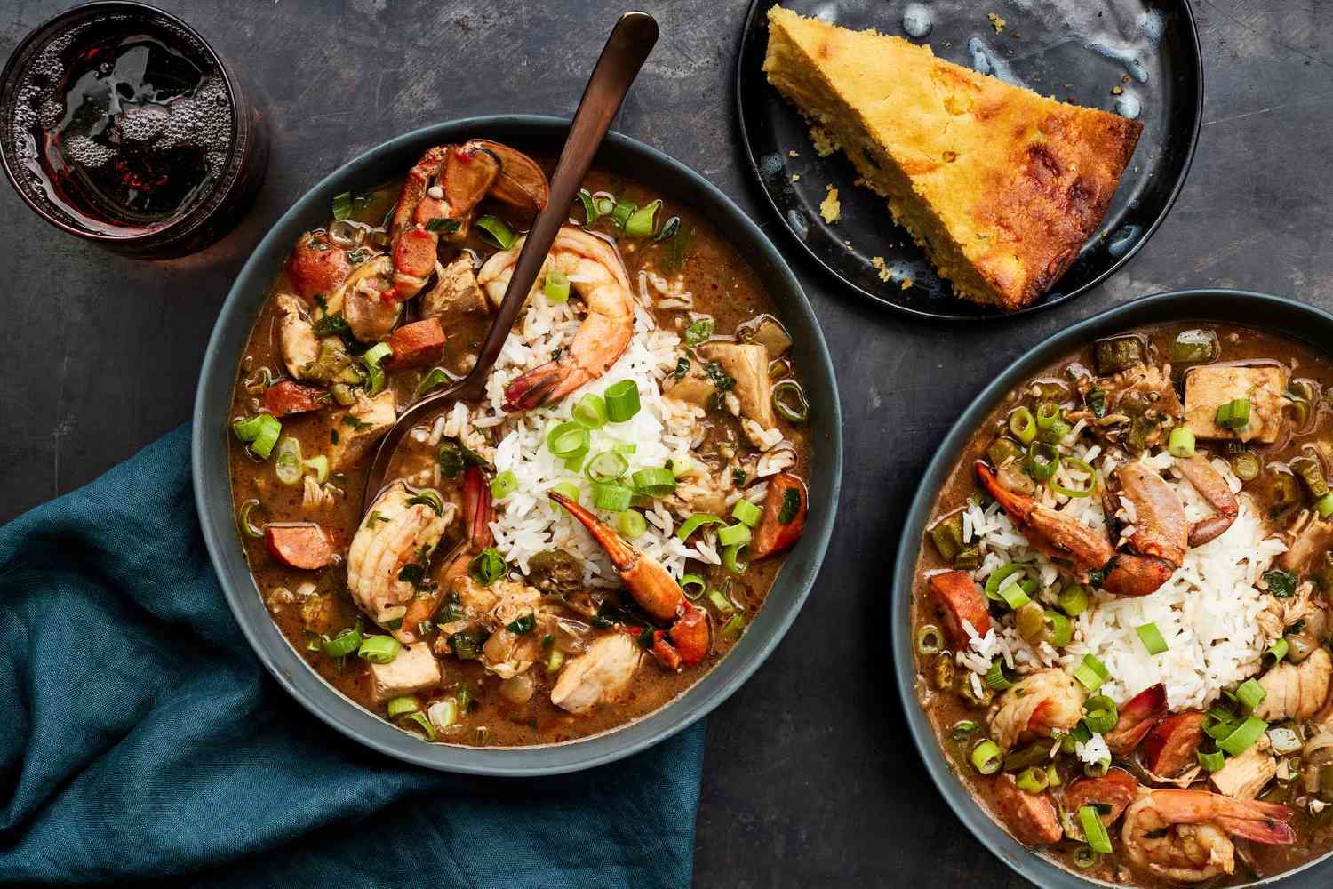 Three bowls of hearty soup with herbs, rice, and bread on a dark table