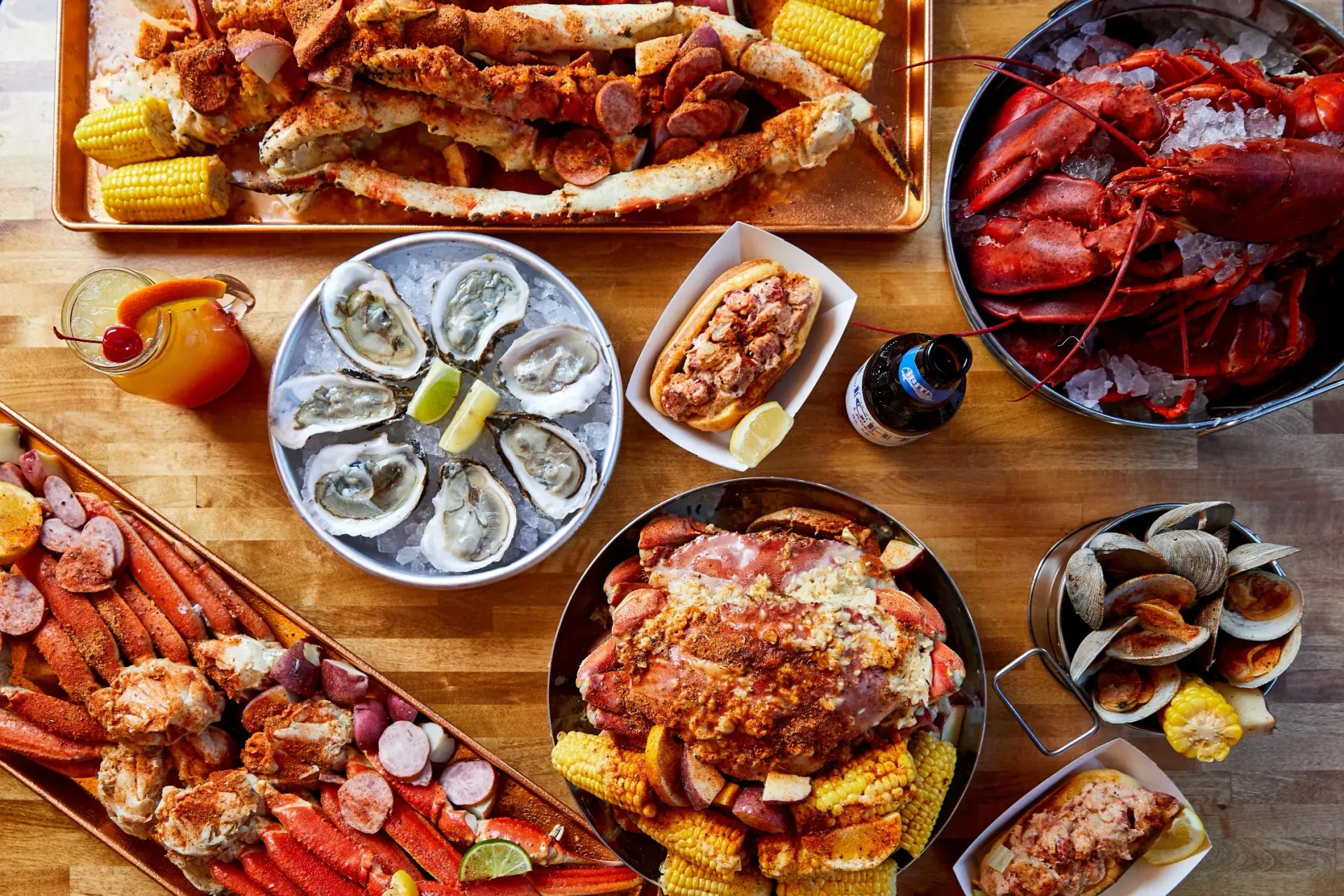 Assorted seafood dishes on wooden table, including oysters, crab, lobster, and grilled fish.