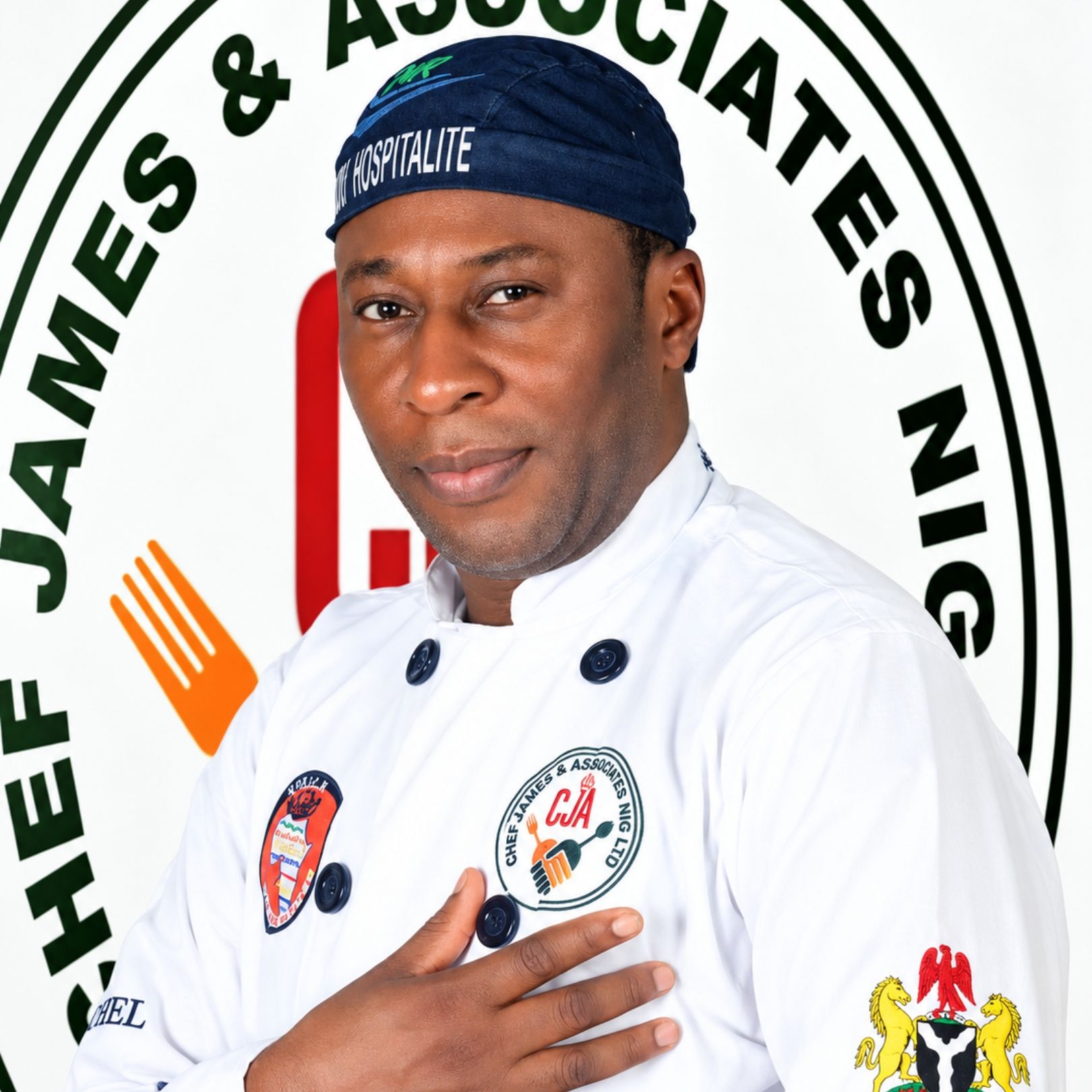 Chef in white uniform and navy cap standing before a James & Associates logo backdrop.