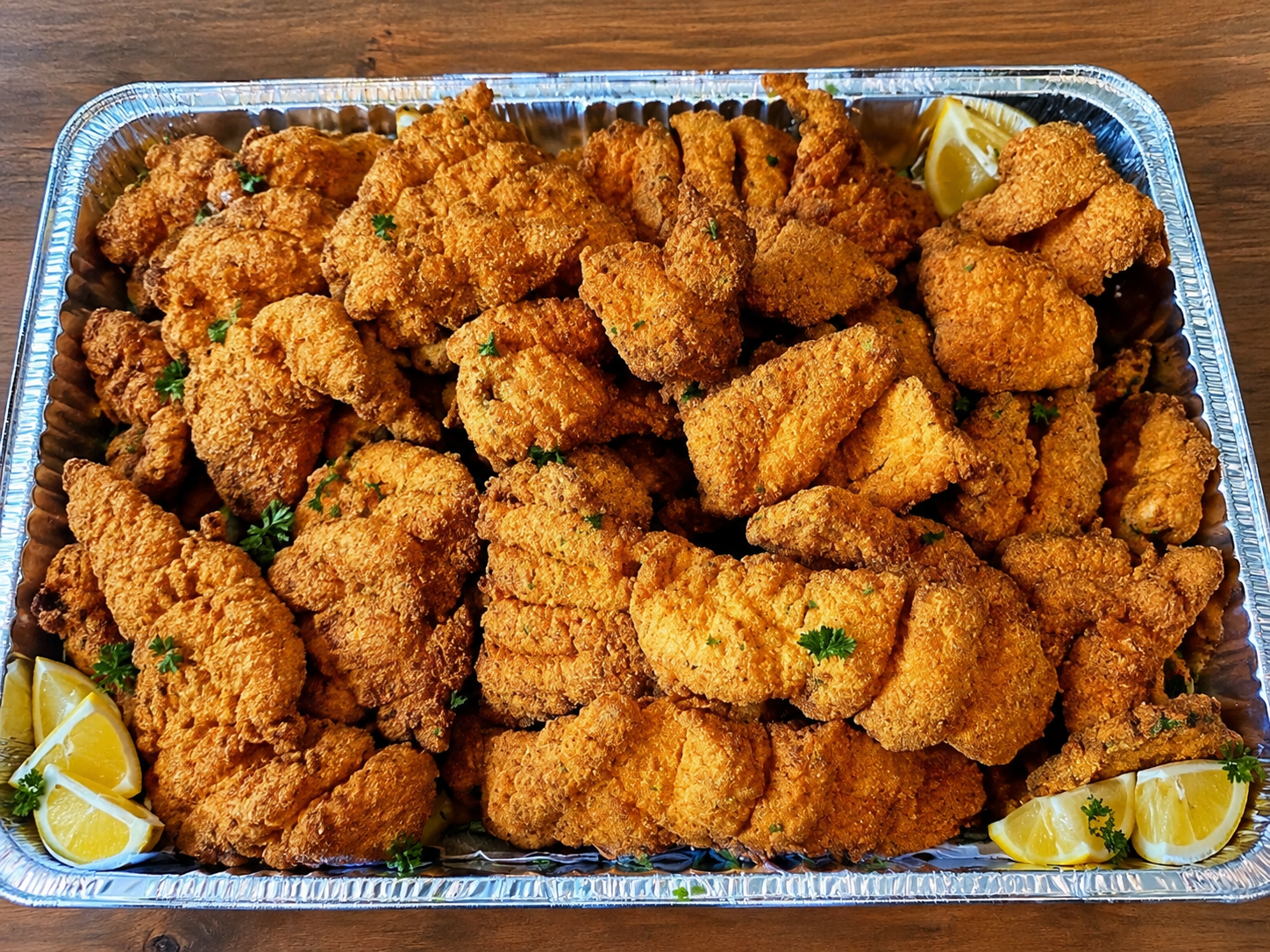 Tray of golden-brown fried seafood pieces with lemon wedges