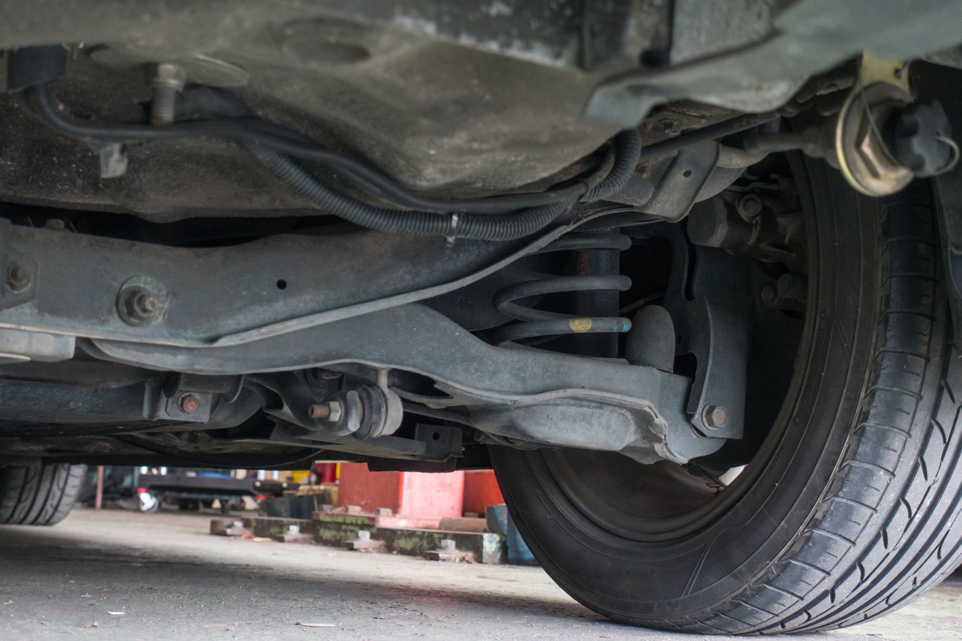 A close up of the underside of a car with a tire. A close up of the underside of a car with a tire.