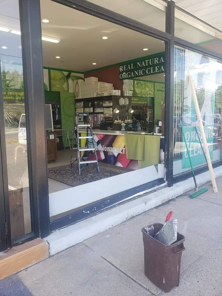 Storefront with glass window display, green awning, and a sidewalk ladder outside