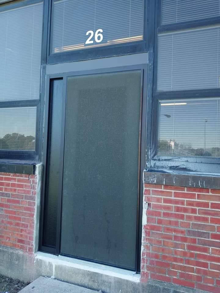 Storefront door with frosted glass and number 26 above it, set in a brick-and-blue facade.