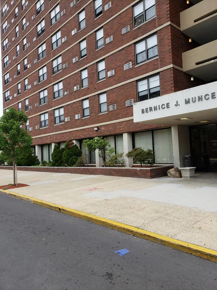 Brick apartment building entrance with a “Service & Munch” sign, sidewalk, and curbside street view