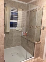 Glass-enclosed tiled shower with a built-in bench and window