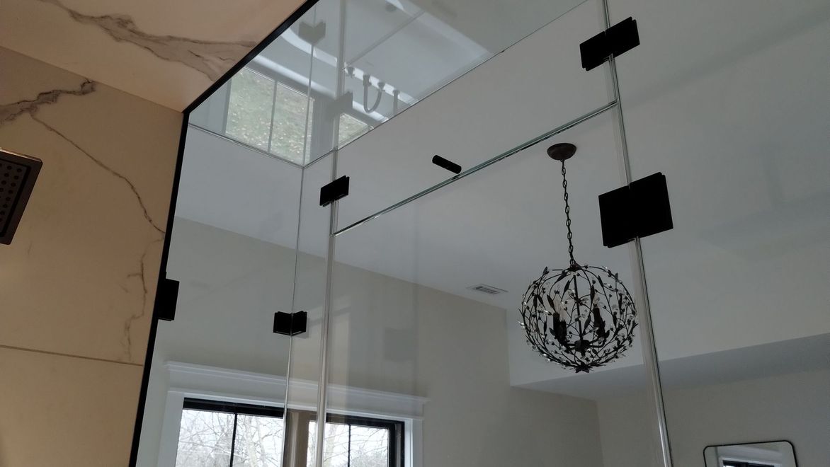 Glass partition with black mounting brackets and hanging pendant light in a bright room