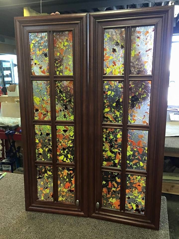 Wooden display cabinet with colorful leaf-patterned glass panels indoors