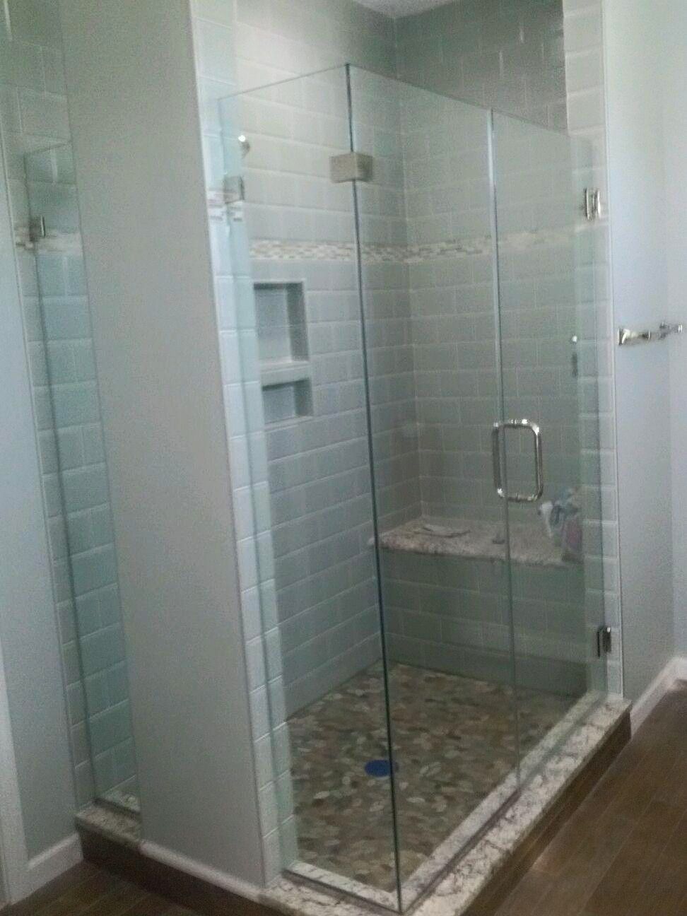 Glass-enclosed tiled shower with a built-in bench and pebble floor in a bathroom