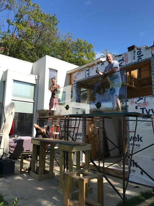 Two workers assembling a scaffold beside a house in bright sunlight