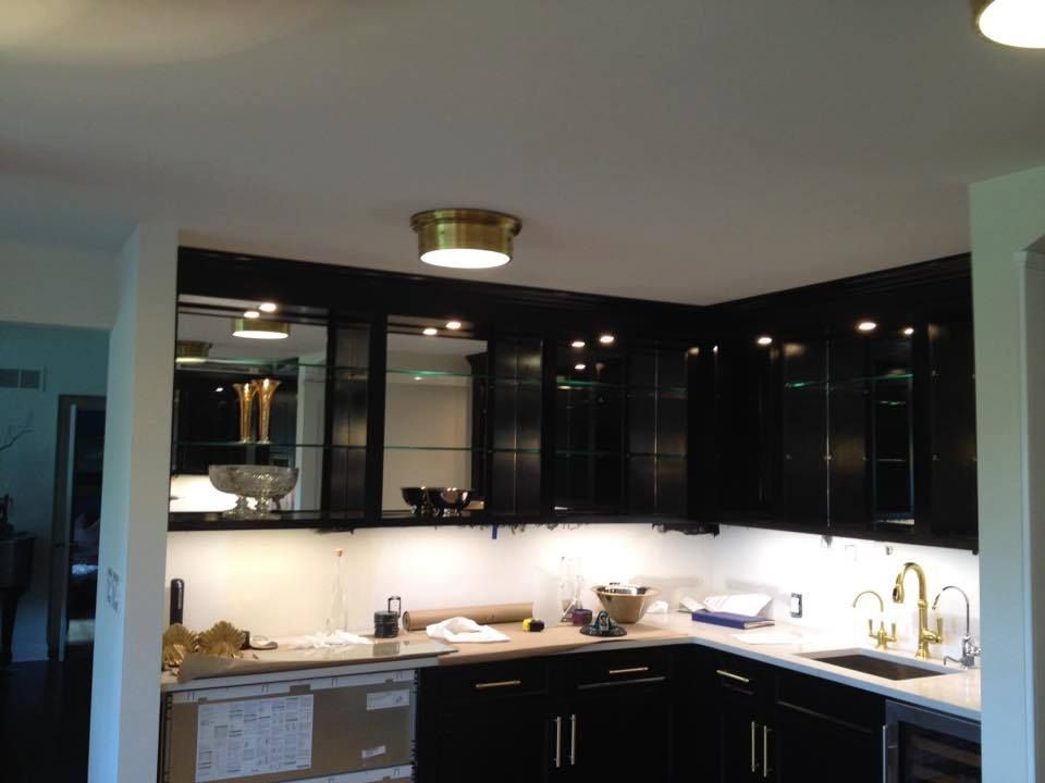 Modern kitchen with black cabinets, white countertops, and a central island under recessed lighting