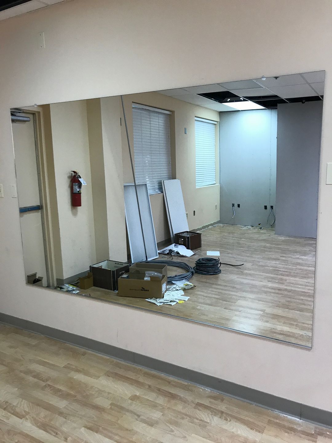 Interior room with a large wall mirror, scattered boxes and debris, and a fire extinguisher on the left wall.