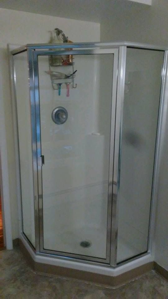 Corner shower stall with clear glass doors and metal frame in a bathroom