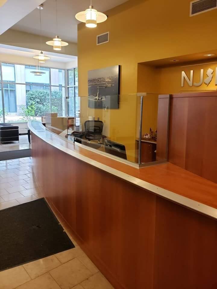 Empty hotel reception desk with wood paneling, white countertop, and yellow walls in a lobby.