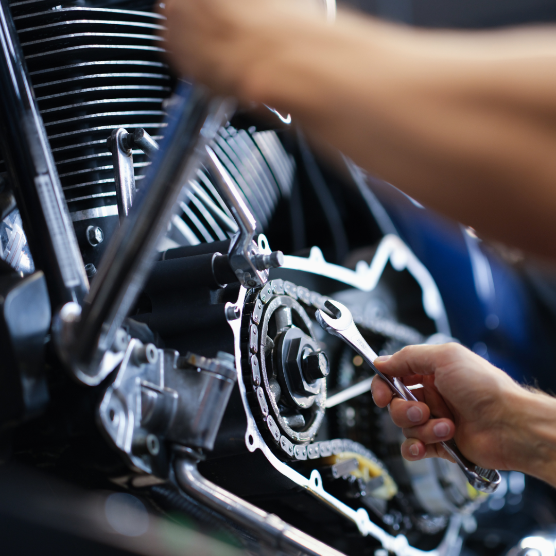 Mechanic working on a motorcycle engine with a wrench; close up with hands.
