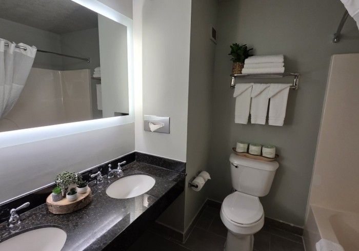 Modern bathroom with black vanity, white sink, toilet, mirror, and towel rack