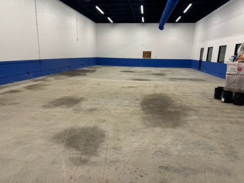 A large empty room with blue walls and a concrete floor.